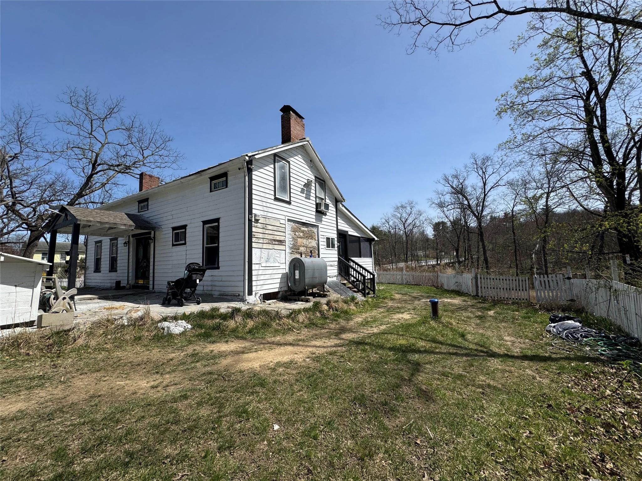50 Hamilton Road Bloomingburg, NY 12721 - Photo 3 of 33 View of property exterior with a chimney, fence, heating fuel, entry steps, and a lawn