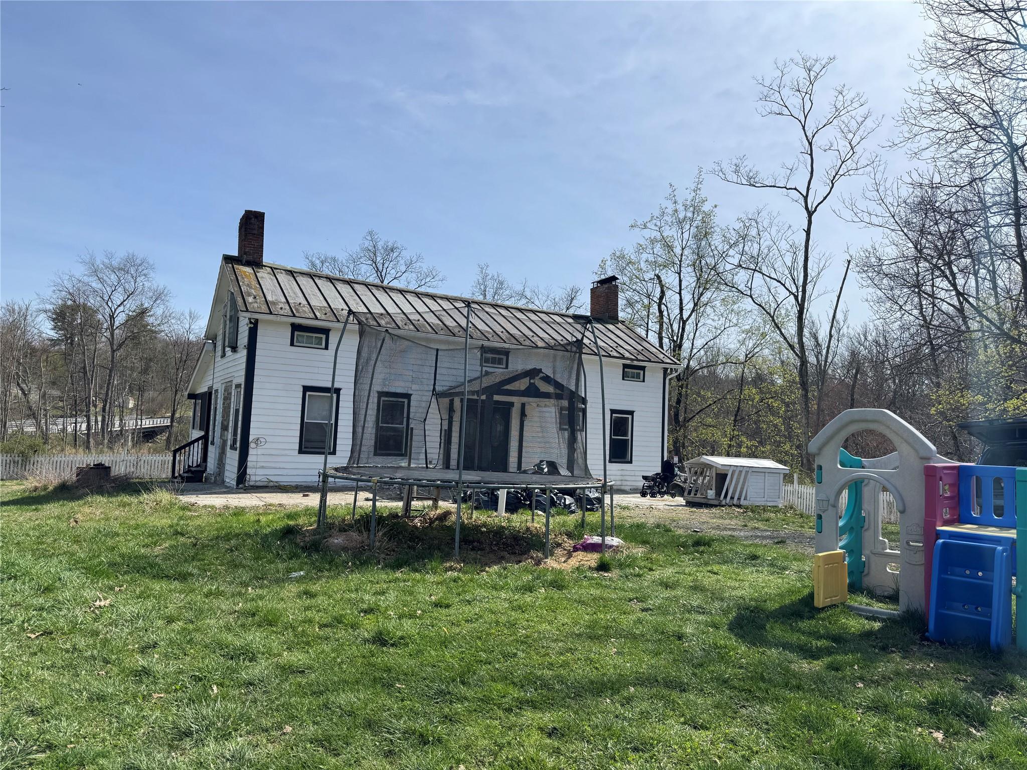 50 Hamilton Road Bloomingburg, NY 12721 - Photo 33 of 33 Back of house featuring a standing seam roof, a chimney, a storage shed, and a trampoline