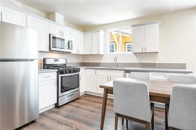 a kitchen with stainless steel appliances a stove a sink refrigerator and white cabinets with wooden floor