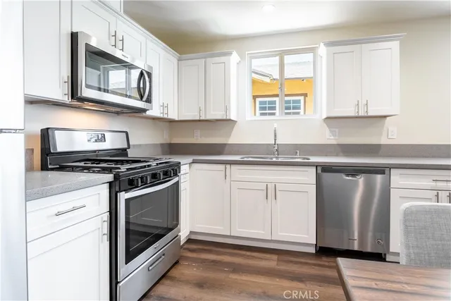 a kitchen with stainless steel appliances granite countertop a stove a sink and a microwave