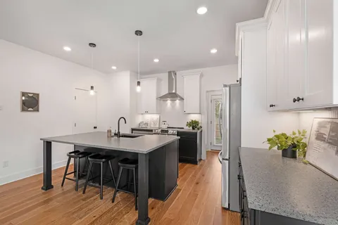 a kitchen with stainless steel appliances kitchen island granite countertop a table chairs stove and refrigerator