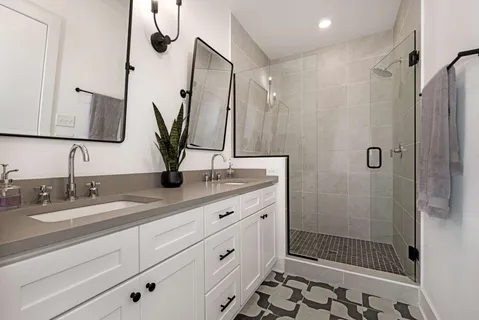 a bathroom with double vanity sink a mirror a glass door a glass door shower and a mirror