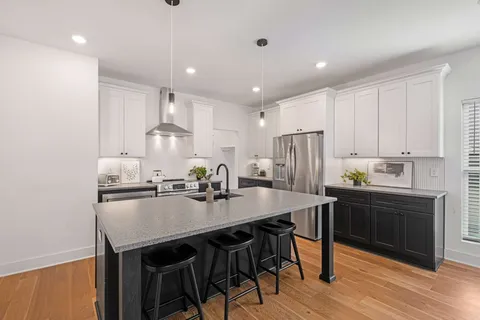 a kitchen with kitchen island cabinets dining table and stainless steel appliances