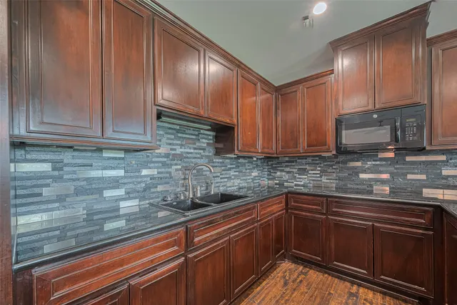 a kitchen with granite countertop wooden cabinets stainless steel appliances and a sink