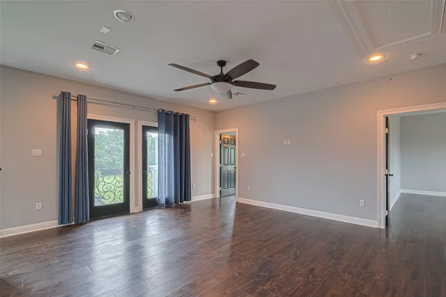 an empty room with wooden floor and a ceiling fan