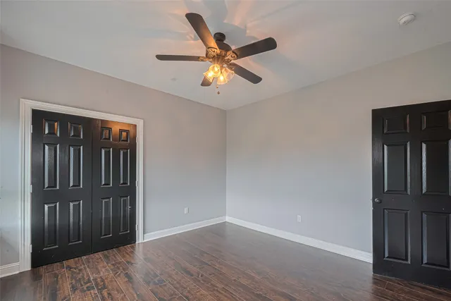 an empty room with wooden floor closet and windows