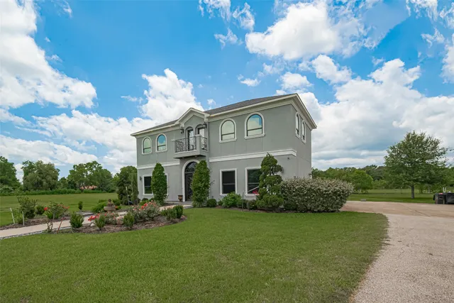 a front view of a house with garden and trees