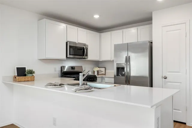 a kitchen with stainless steel appliances a refrigerator a sink a stove a microwave and wooden cabinets