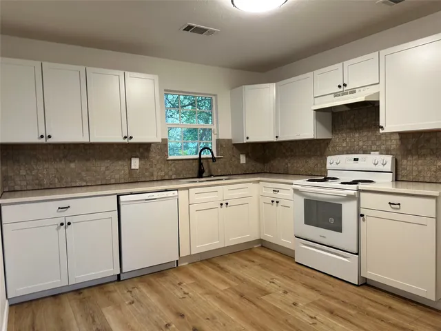 a kitchen with granite countertop white cabinets and white appliances