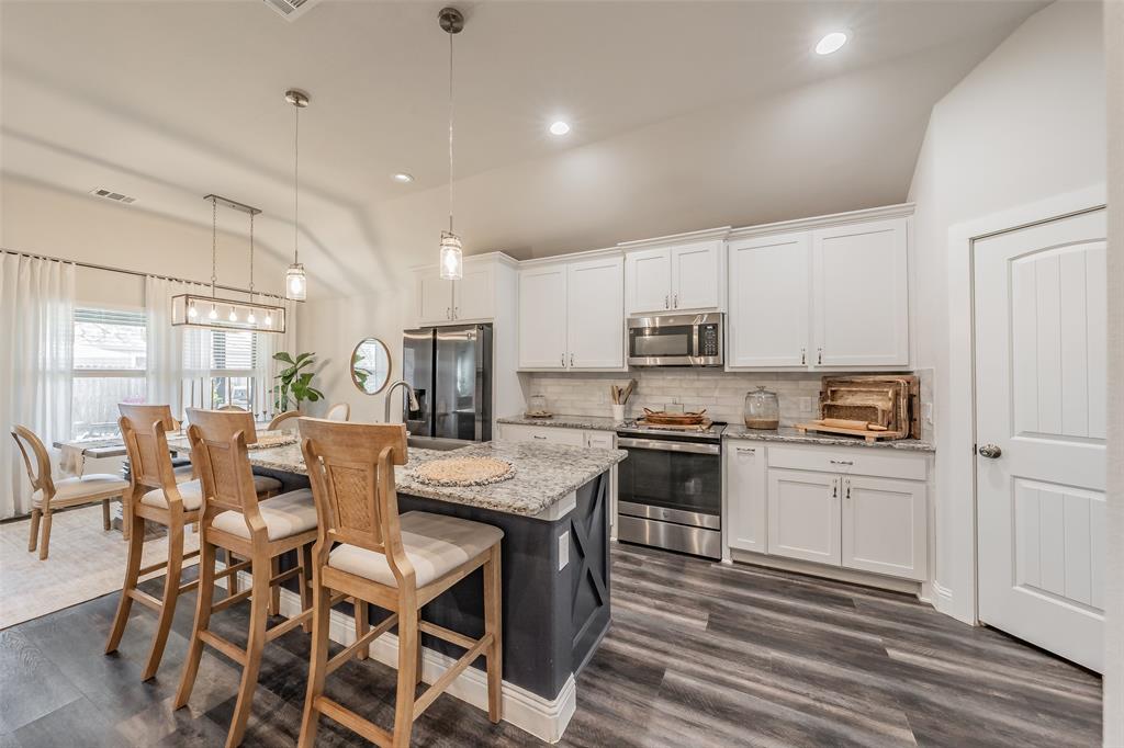 141 Maverick Lane Pilot Point, TX 76258 - Photo 19 of 40 a kitchen with stainless steel appliances granite countertop a stove top oven a refrigerator a sink and white cabinets with wooden floor