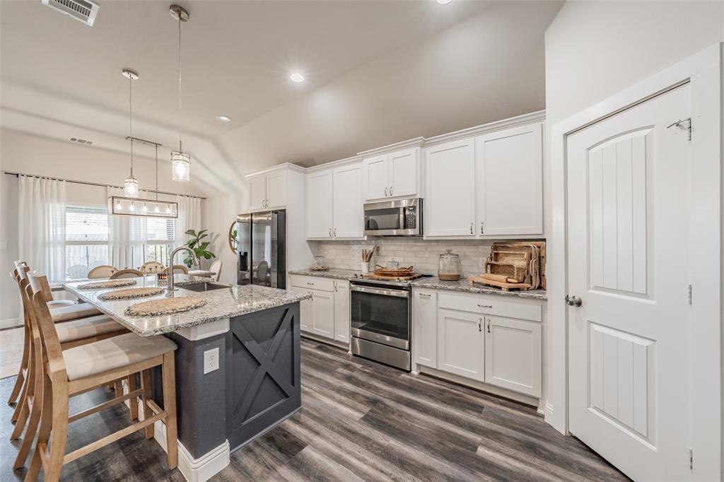 141 Maverick Lane Pilot Point, TX 76258 - Photo 20 of 40 a kitchen with stainless steel appliances kitchen island granite countertop a stove a sink dishwasher and a refrigerator with wooden floor