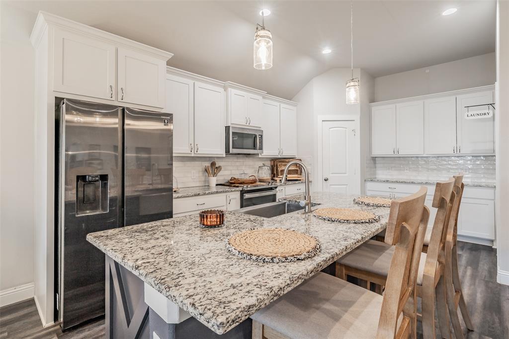 141 Maverick Lane Pilot Point, TX 76258 - Photo 21 of 40 a kitchen with granite countertop kitchen island a refrigerator a stove a dining table and chairs