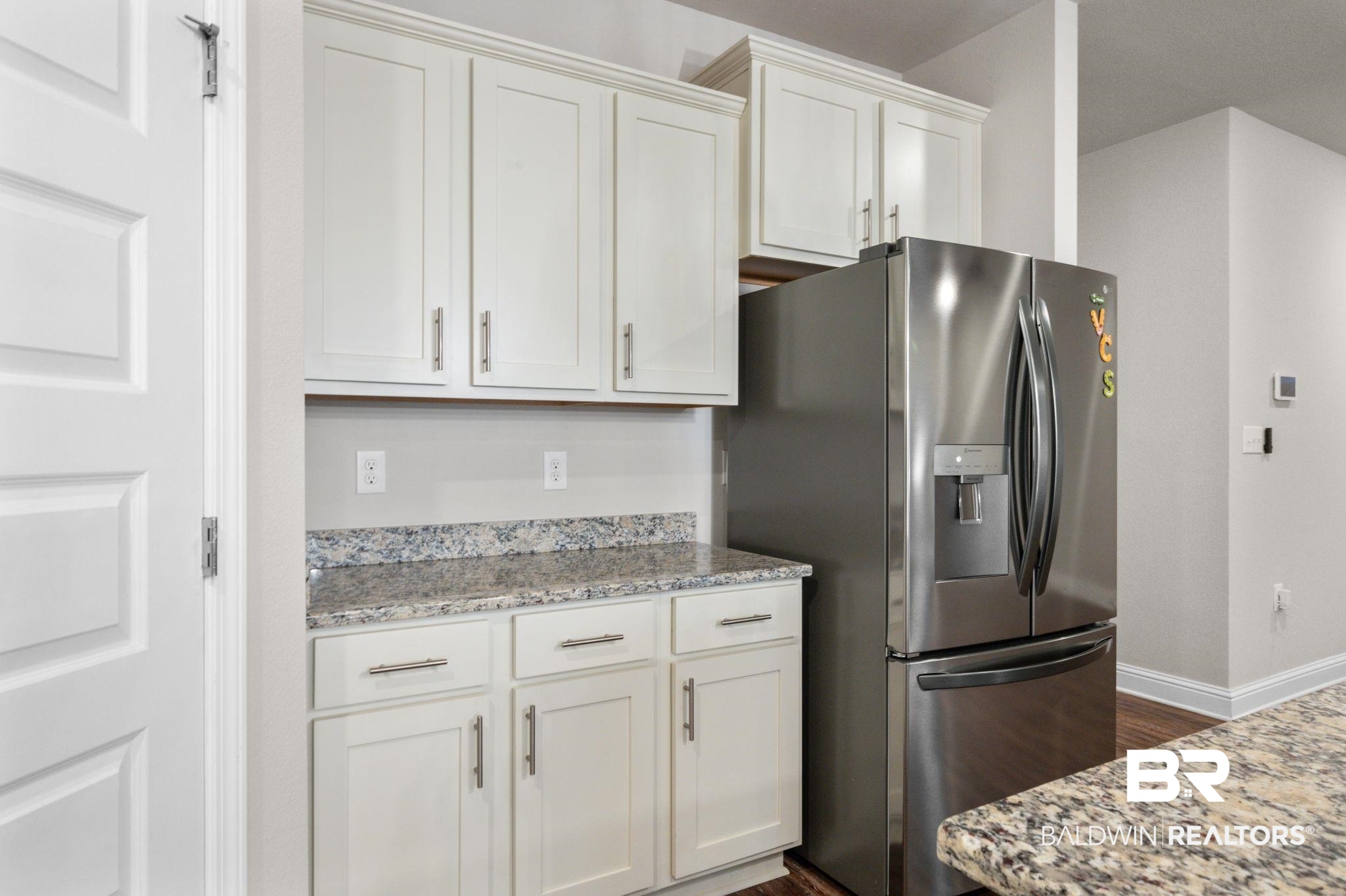 24769 Slater Mill Road Daphne, AL 36526 - Photo 12 of 38 Kitchen featuring light stone countertops, dark wood-type flooring, white cabinets, and stainless steel fridge with ice dispenser