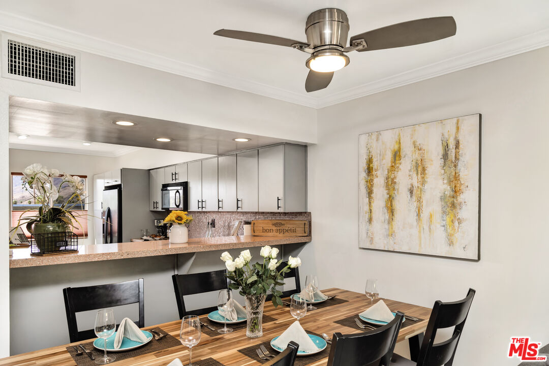 277 East Alejo Road, Unit 119 Palm Springs, CA 92262 - Photo 11 of 46 a kitchen with a table chairs refrigerator and wooden cabinets