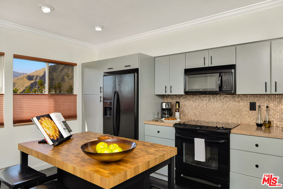 277 East Alejo Road, Unit 119 Palm Springs, CA 92262 - Photo 14 of 46 a kitchen with stainless steel appliances granite countertop a stove a refrigerator a sink a dining table and chairs