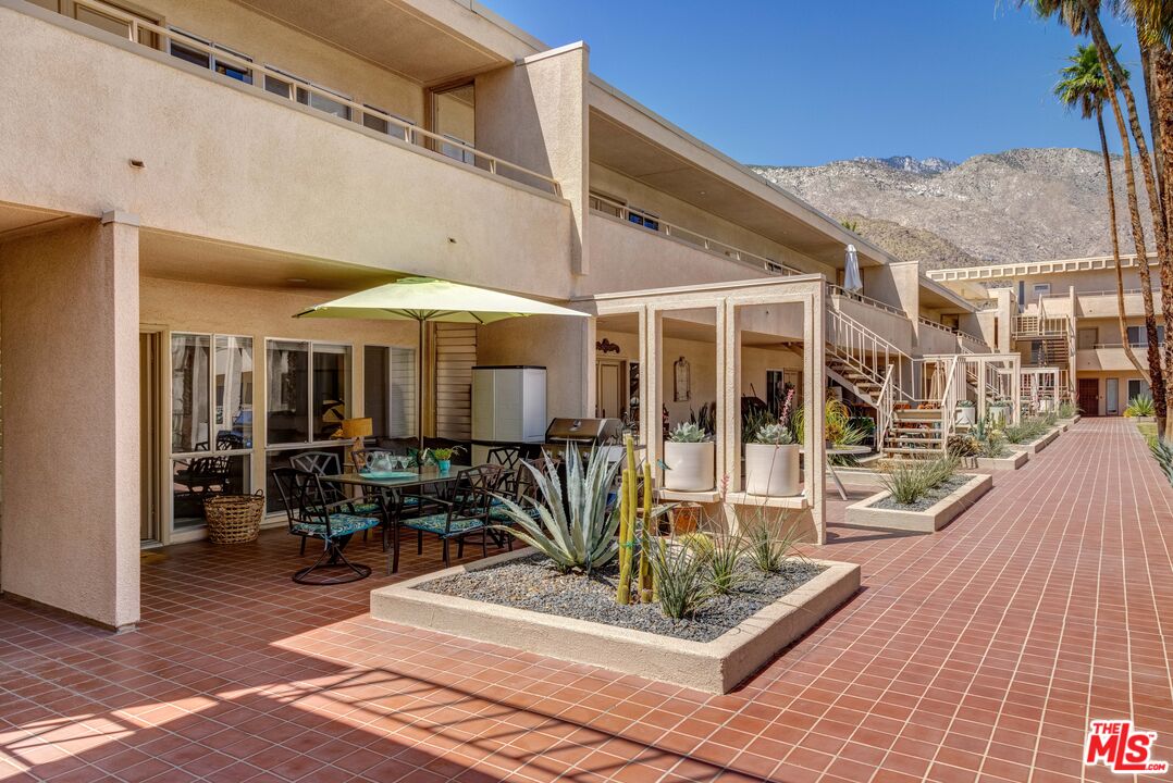 277 East Alejo Road, Unit 119 Palm Springs, CA 92262 - Photo 39 of 46 a patio with a table and chairs under an umbrella