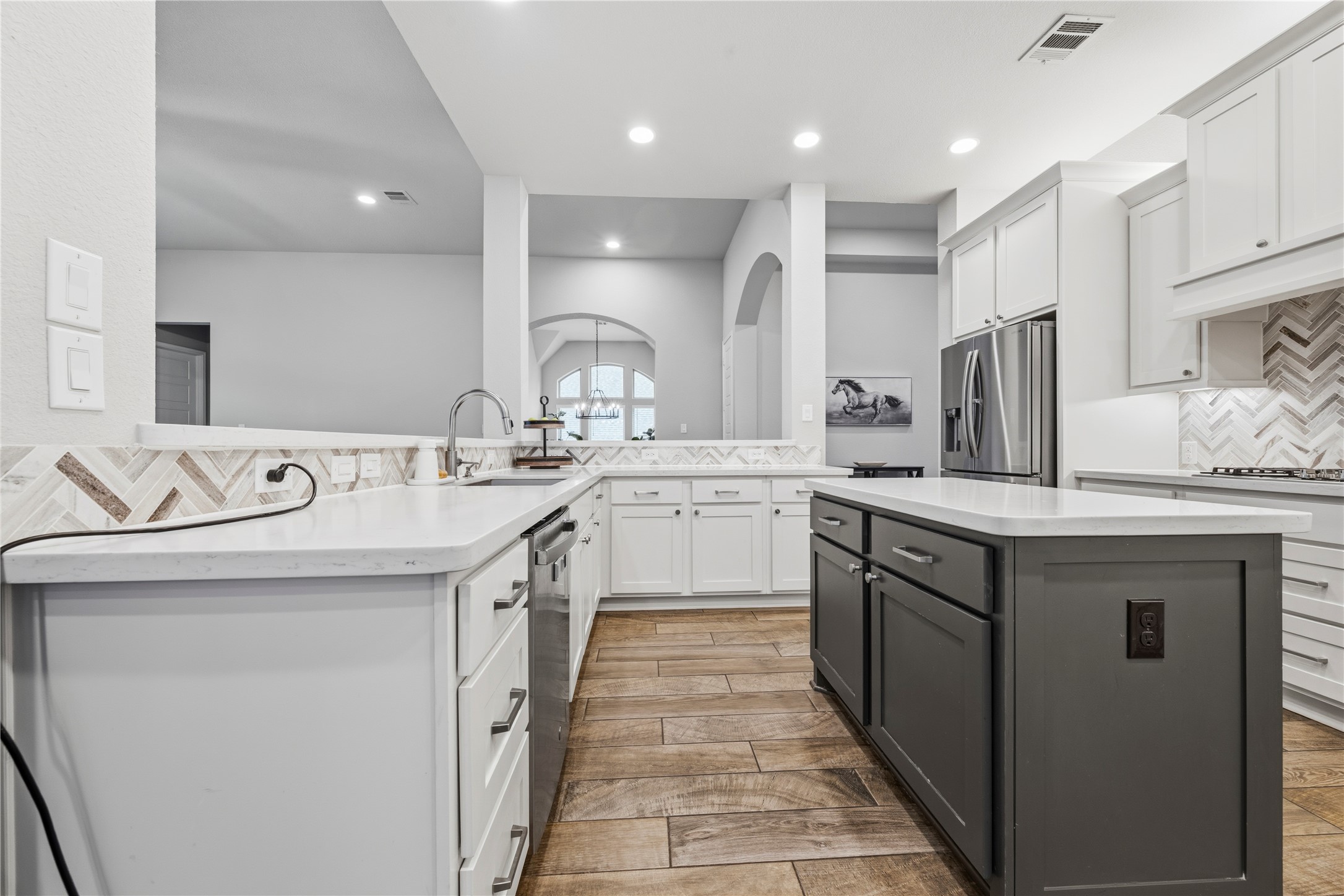 140 Catani Loop Georgetown, TX 78628 - Photo 15 of 36 A contemporary kitchen features a contrasting island, pristine countertops, and wood-look flooring.