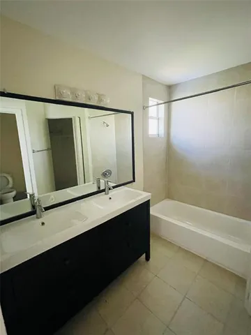 a bathroom with a double vanity sink a toilet and a bathtub