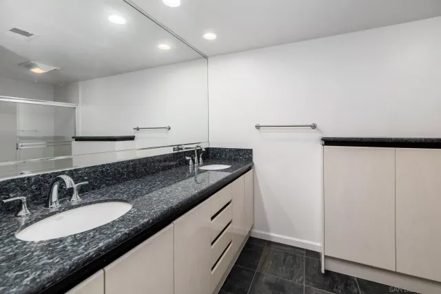 a bathroom with a granite countertop sink a toilet a mirror and shower