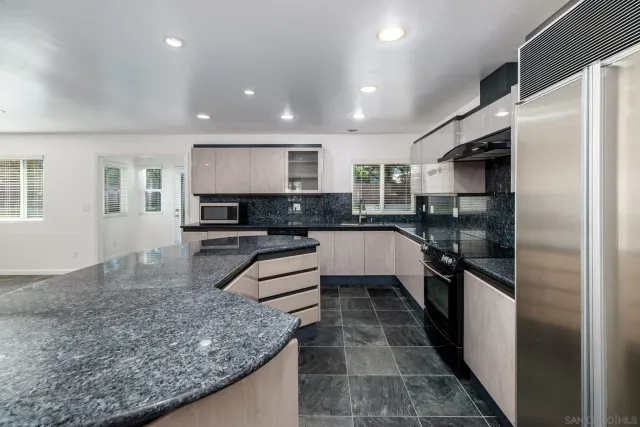 a large kitchen with stainless steel appliances kitchen island granite countertop a sink a stove a microwave and a refrigerator