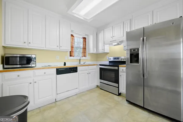 a kitchen with granite countertop white cabinets and stainless steel appliances