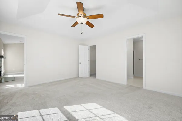 an empty room with ceiling fan and window