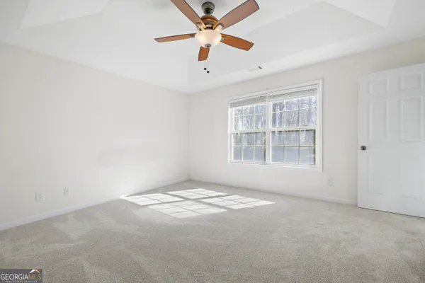 an empty room with windows and fan