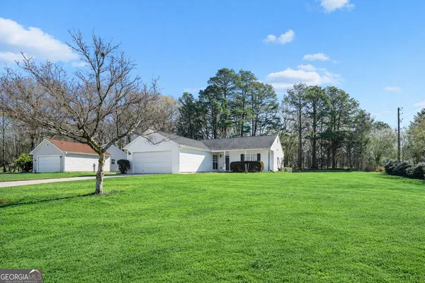 a house that is sitting in middle of grass and trees in the background