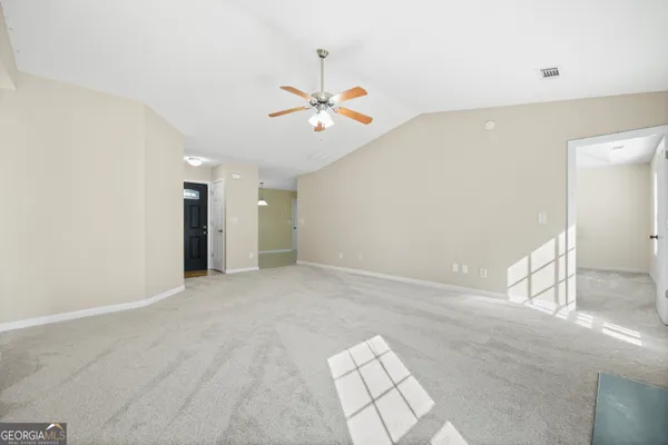 an empty room with chandelier fan and windows