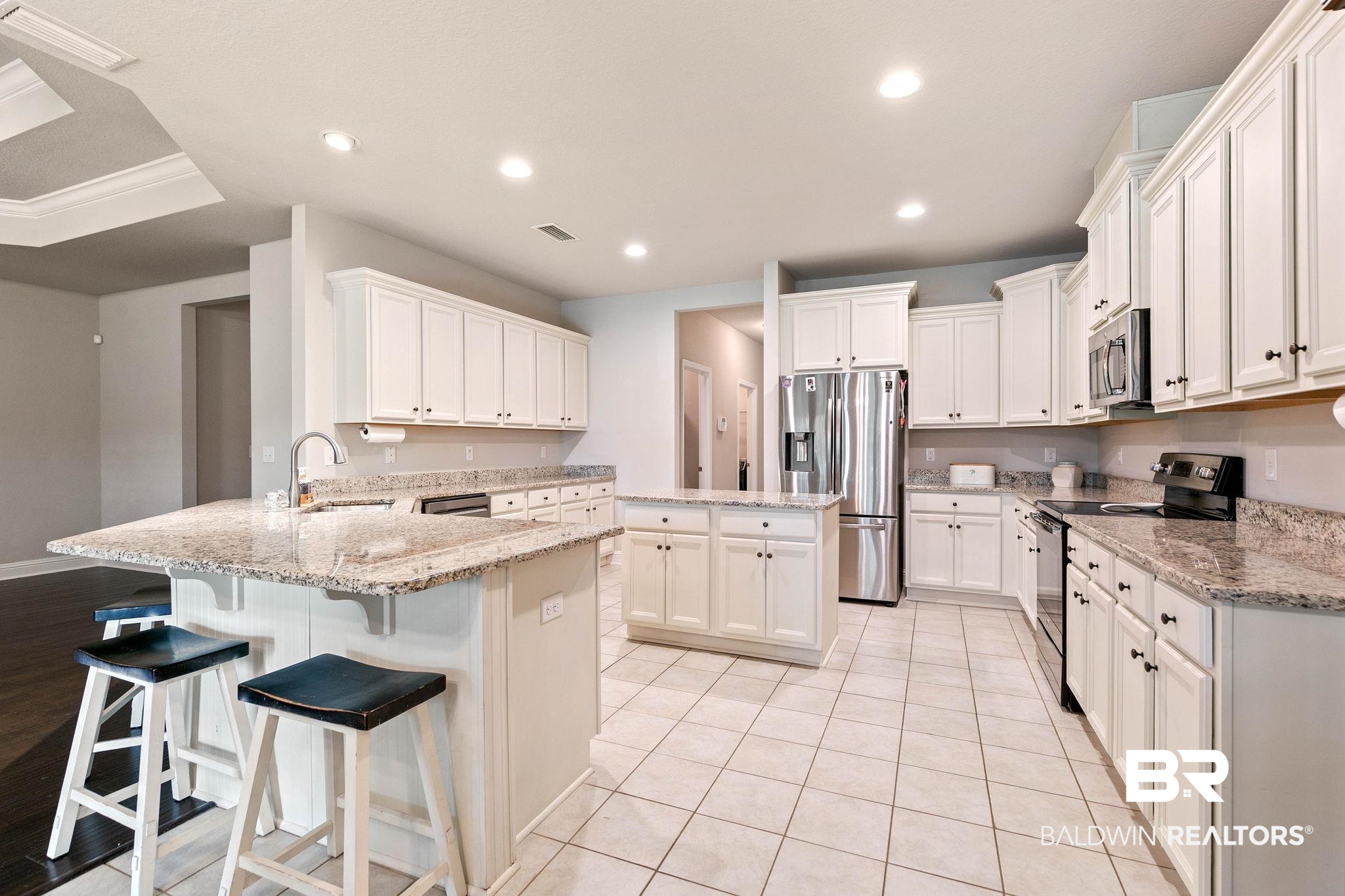 12750 B Jenkins Pit Road Daphne, AL 36527 - Photo 27 of 89 Kitchen featuring stainless steel appliances, a peninsula, a kitchen bar, a kitchen island, and white cabinetry
