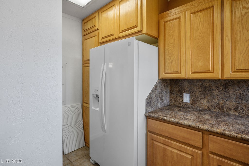 633 5th Street Boulder City, NV 89005 - Photo 12 of 29 Kitchen with a textured wall, white fridge with ice dispenser, decorative backsplash, dark stone counters, and light tile patterned floors