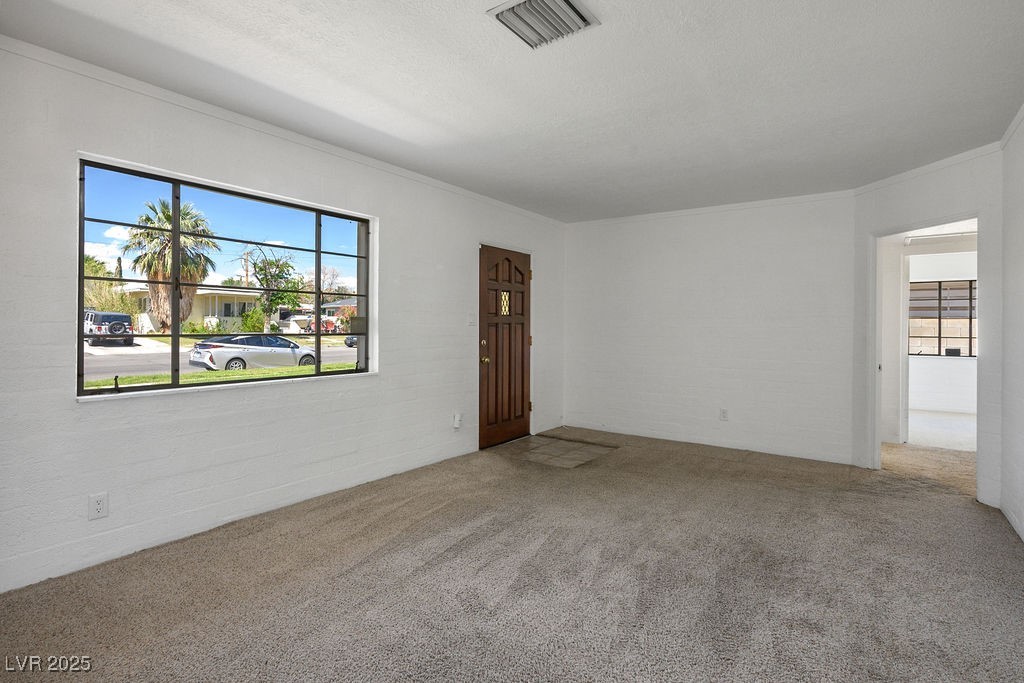 633 5th Street Boulder City, NV 89005 - Photo 15 of 29 Empty room featuring plenty of natural light, carpet floors, ornamental molding, and a textured ceiling
