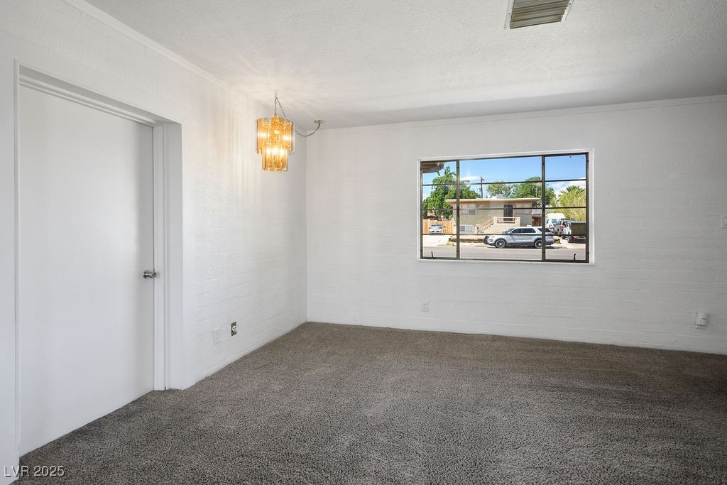 633 5th Street Boulder City, NV 89005 - Photo 16 of 29 Unfurnished room featuring ornamental molding, a chandelier, dark colored carpet, and a textured ceiling
