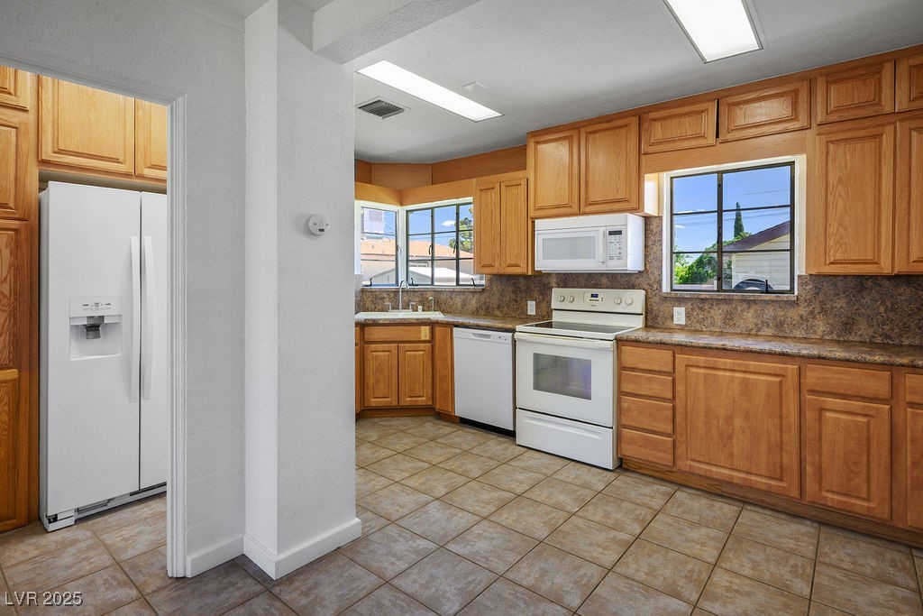 633 5th Street Boulder City, NV 89005 - Photo 10 of 29 Kitchen with white appliances, backsplash, and brown cabinets