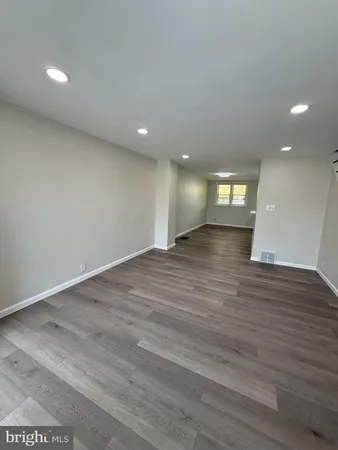 an empty room with wooden floor and natural light