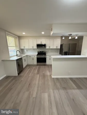a large kitchen with kitchen island a sink dishwasher a stove and a refrigerator with wooden floor
