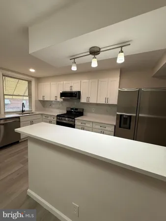 a kitchen with stainless steel appliances a stove top oven a sink a refrigerator a center island and cabinets
