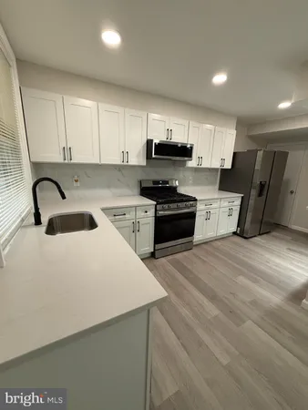 a kitchen with stainless steel appliances a sink a stove top oven a refrigerator and cabinets
