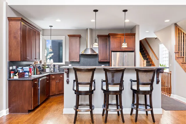 a kitchen with stainless steel appliances kitchen island granite countertop a table chairs in it and wooden floors