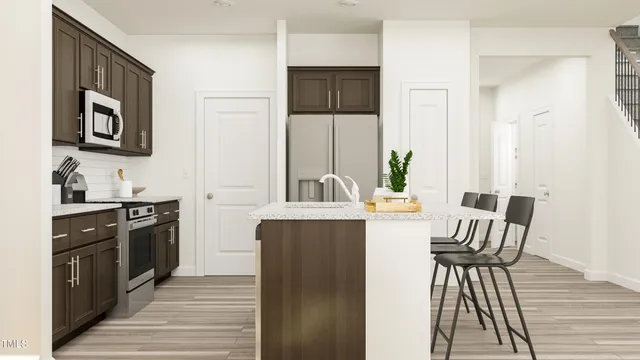 a kitchen with stainless steel appliances granite countertop a dining table chairs and a refrigerator