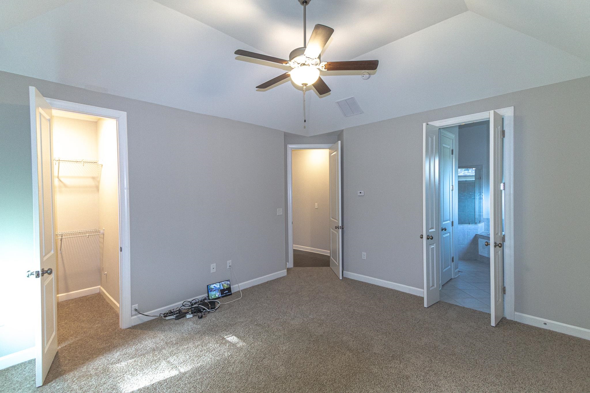 2422 Crimson Ridge Lane Cordova, TN 38016 - Photo 11 of 36 Unfurnished bedroom featuring a walk in closet, light colored carpet, vaulted ceiling, and a ceiling fan