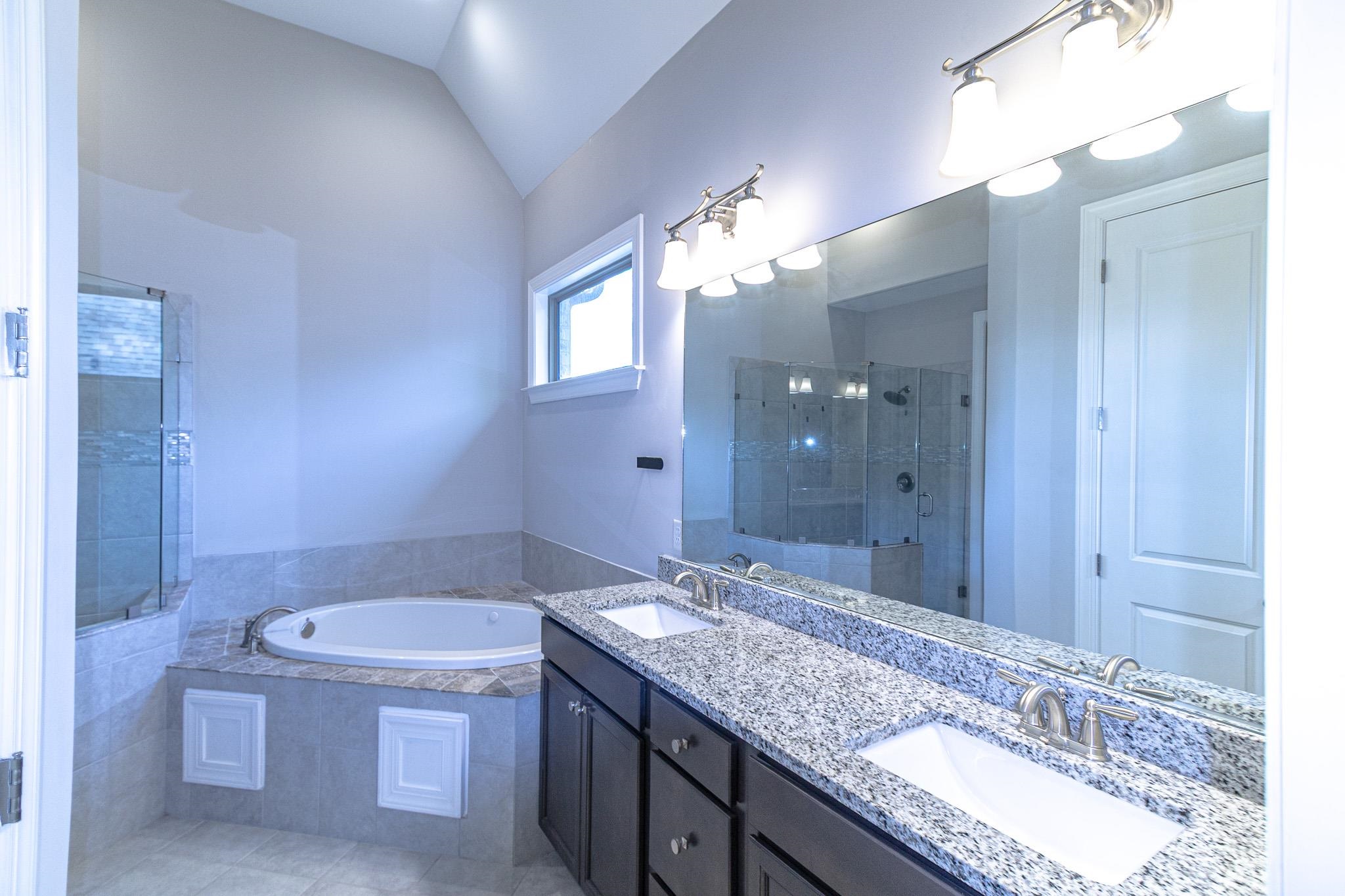 2422 Crimson Ridge Lane Cordova, TN 38016 - Photo 16 of 36 Bathroom featuring double vanity, a stall shower, lofted ceiling, a garden tub, and light tile patterned floors