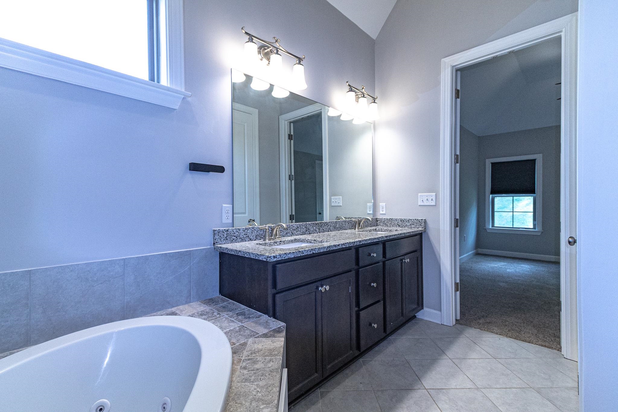 2422 Crimson Ridge Lane Cordova, TN 38016 - Photo 20 of 36 Bathroom with double vanity, light tile patterned floors, light colored carpet, and a jetted tub