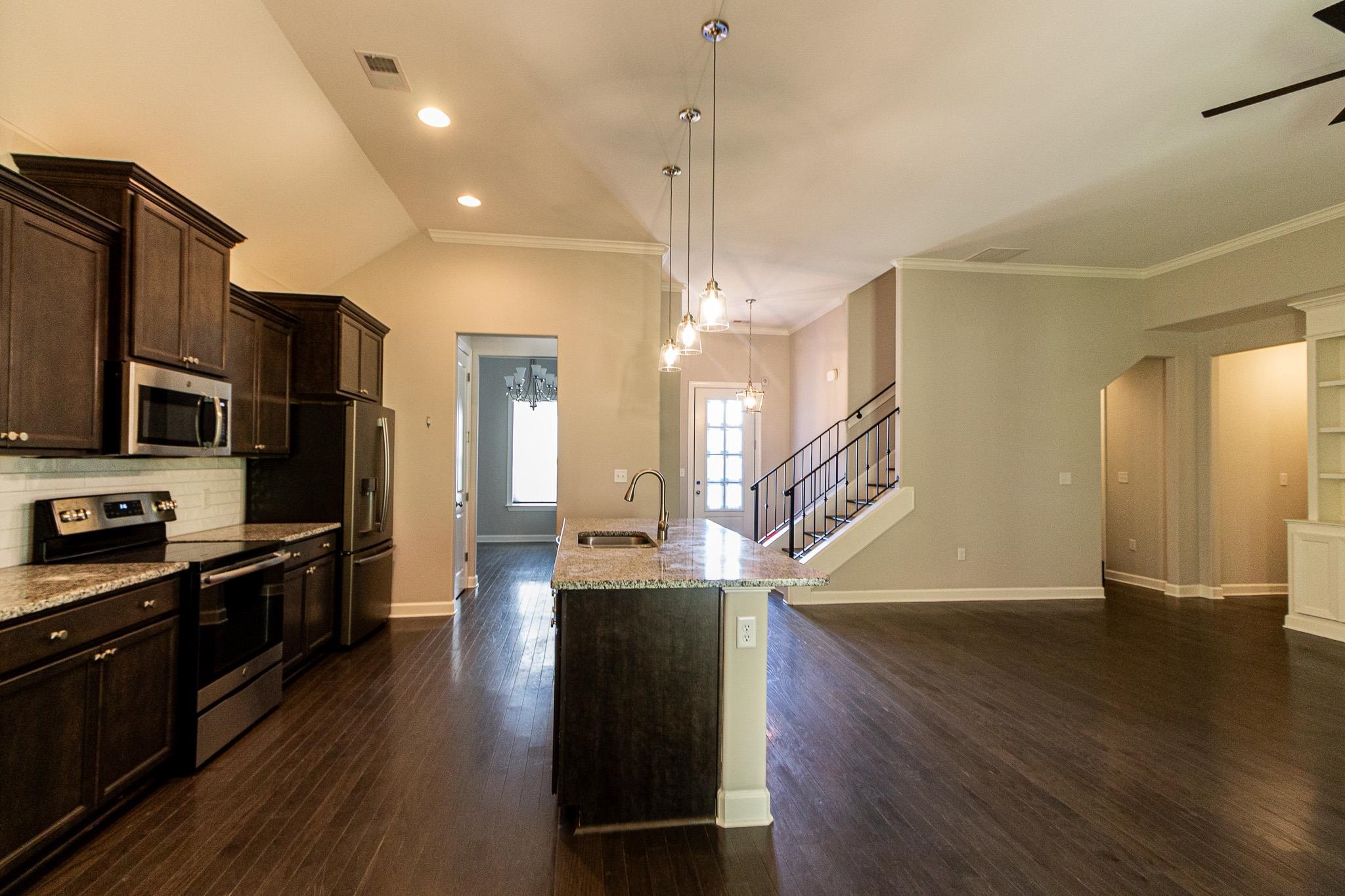 2422 Crimson Ridge Lane Cordova, TN 38016 - Photo 4 of 36 Kitchen featuring dark wood finish cabinets, stainless steel appliances, light stone countertops, ornamental molding, and dark wood-style floors