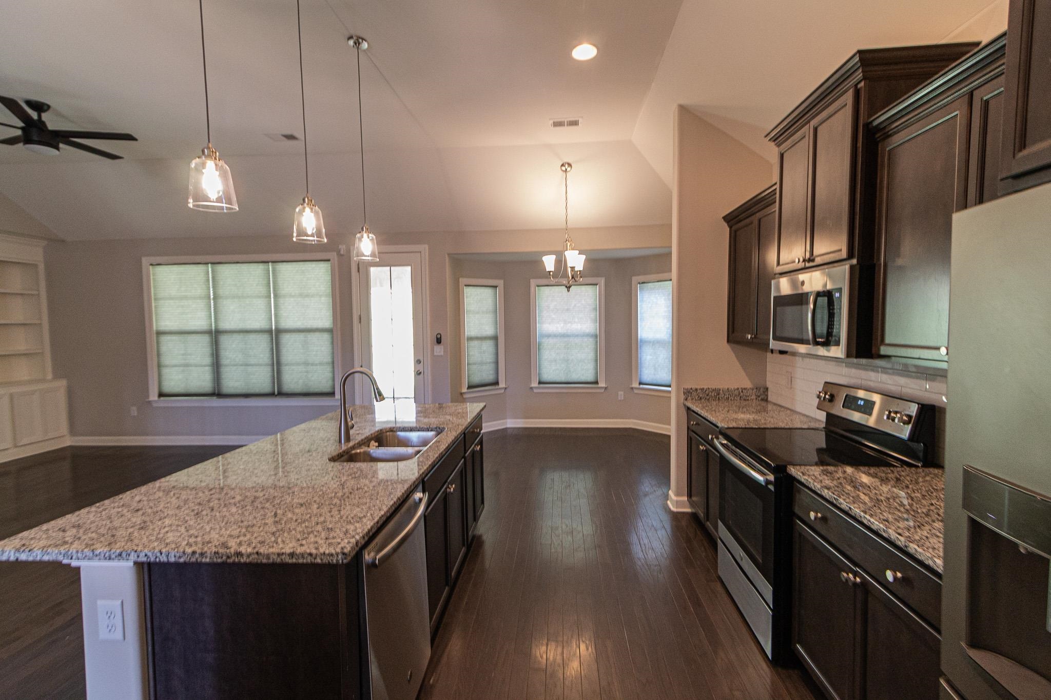 2422 Crimson Ridge Lane Cordova, TN 38016 - Photo 6 of 36 Kitchen featuring stainless steel appliances, dark wood finish cabinets, dark wood-type flooring, light stone countertops, and lofted ceiling