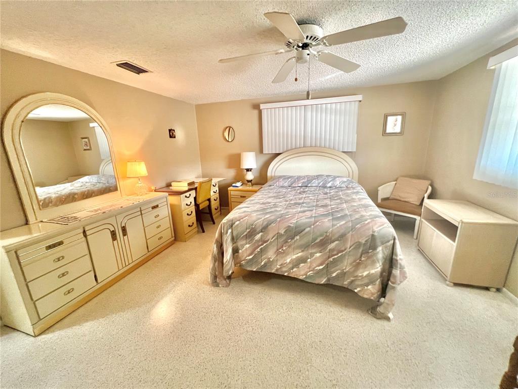 5145 Cicero Drive New Port Richey, FL 34652 - Photo 12 of 19 a bedroom with a bed a mirror on dresser and a chandelier