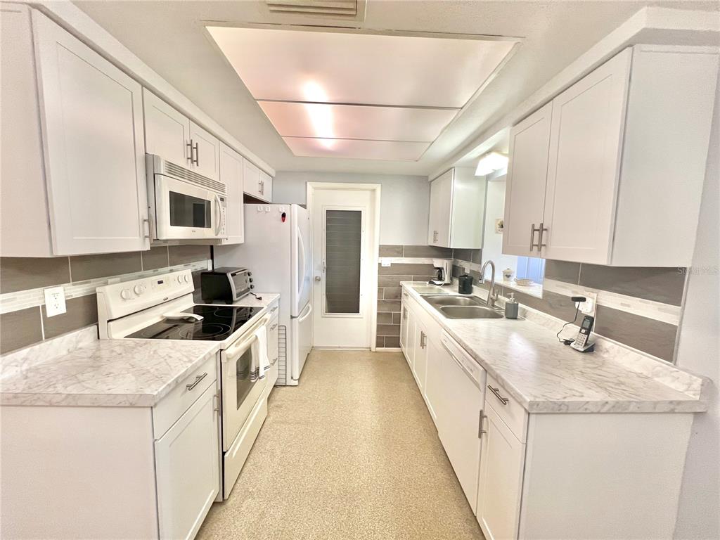 5145 Cicero Drive New Port Richey, FL 34652 - Photo 5 of 19 a large white kitchen with stainless steel appliances kitchen island granite countertop a sink and cabinets