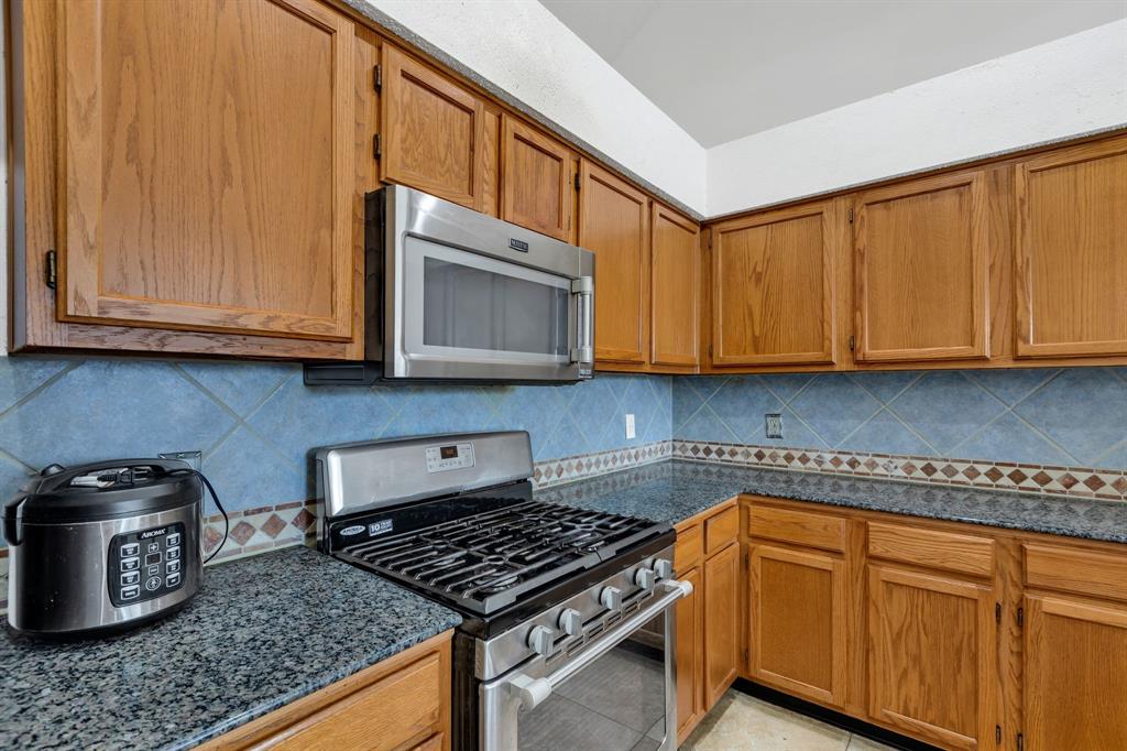 8405 Spinnaker Cove Rowlett, TX 75089 - Photo 13 of 30 a kitchen with stainless steel appliances granite countertop a stove a microwave and cabinets