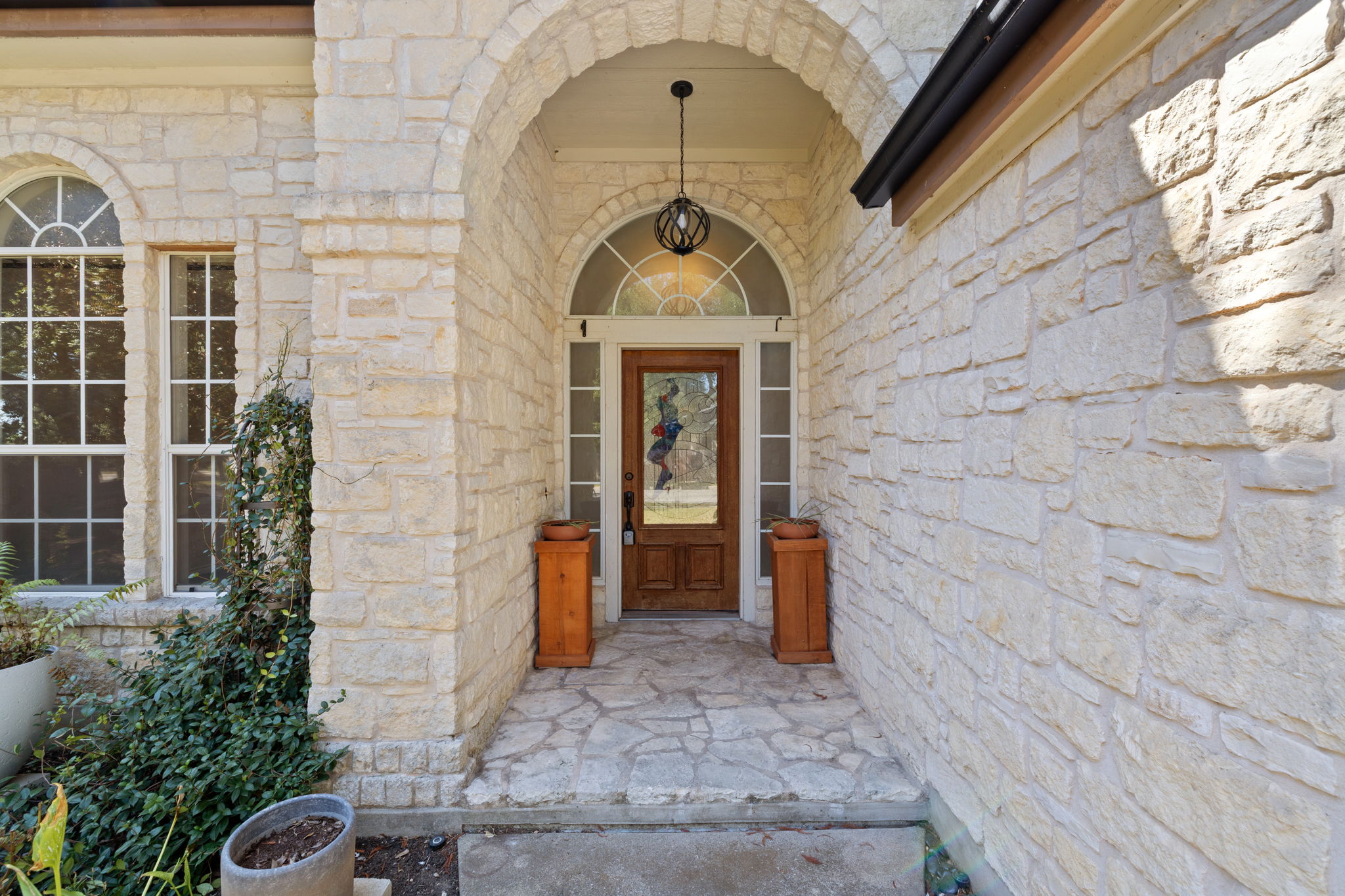 2211 Spring Hollow Path Round Rock, TX 78681 - Photo 3 of 36 An arched stone entryway leads to a classic wood front door with sidelights.