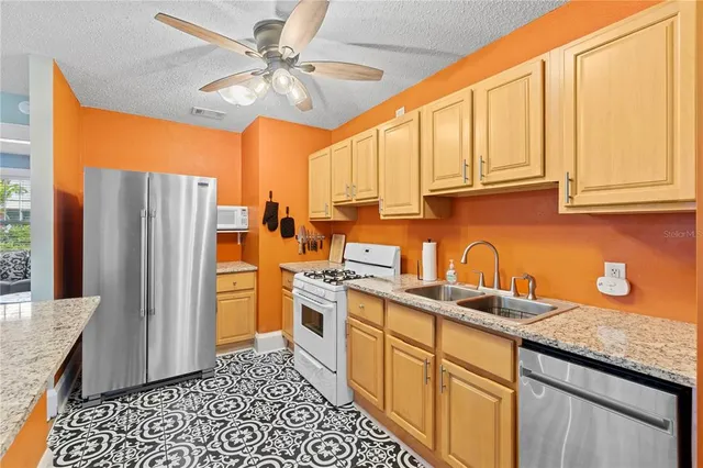 a kitchen with stainless steel appliances granite countertop a refrigerator a sink a stove and island